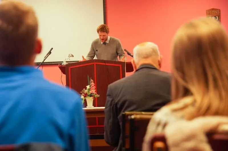 The pastor preaching from the pulpit, seen from behind the congregation